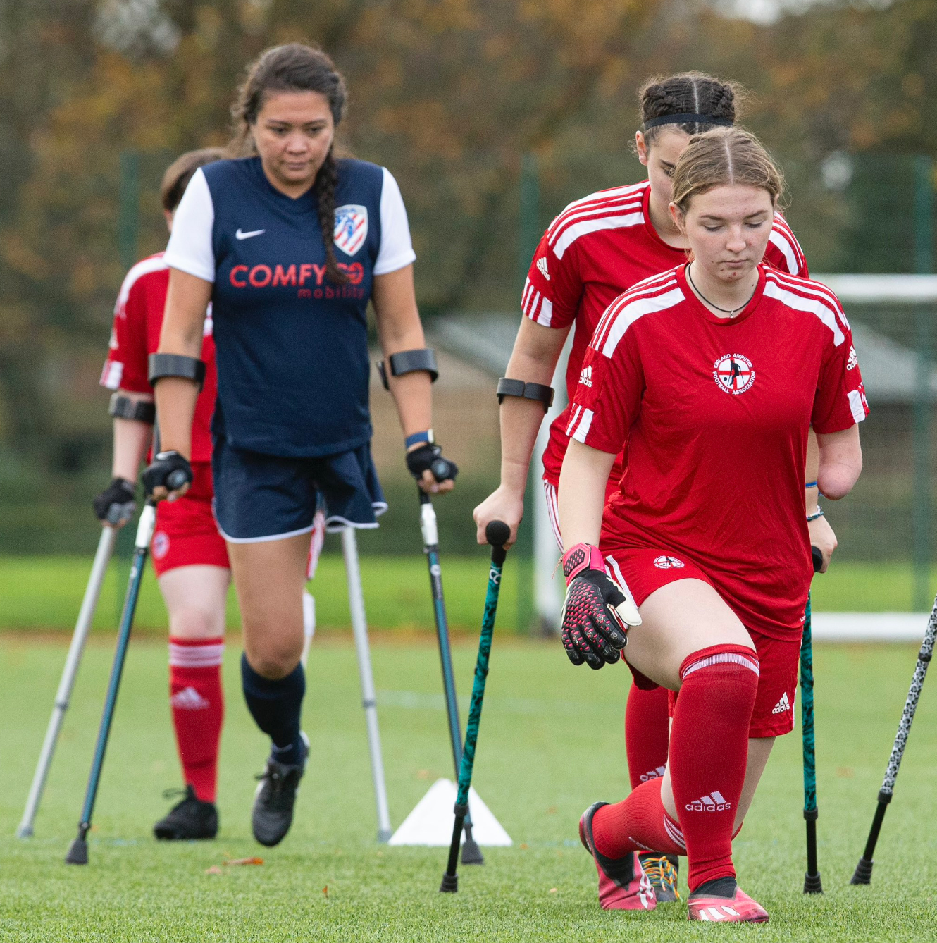 Tate and other players warm up on a grass pitch, in red England kit.